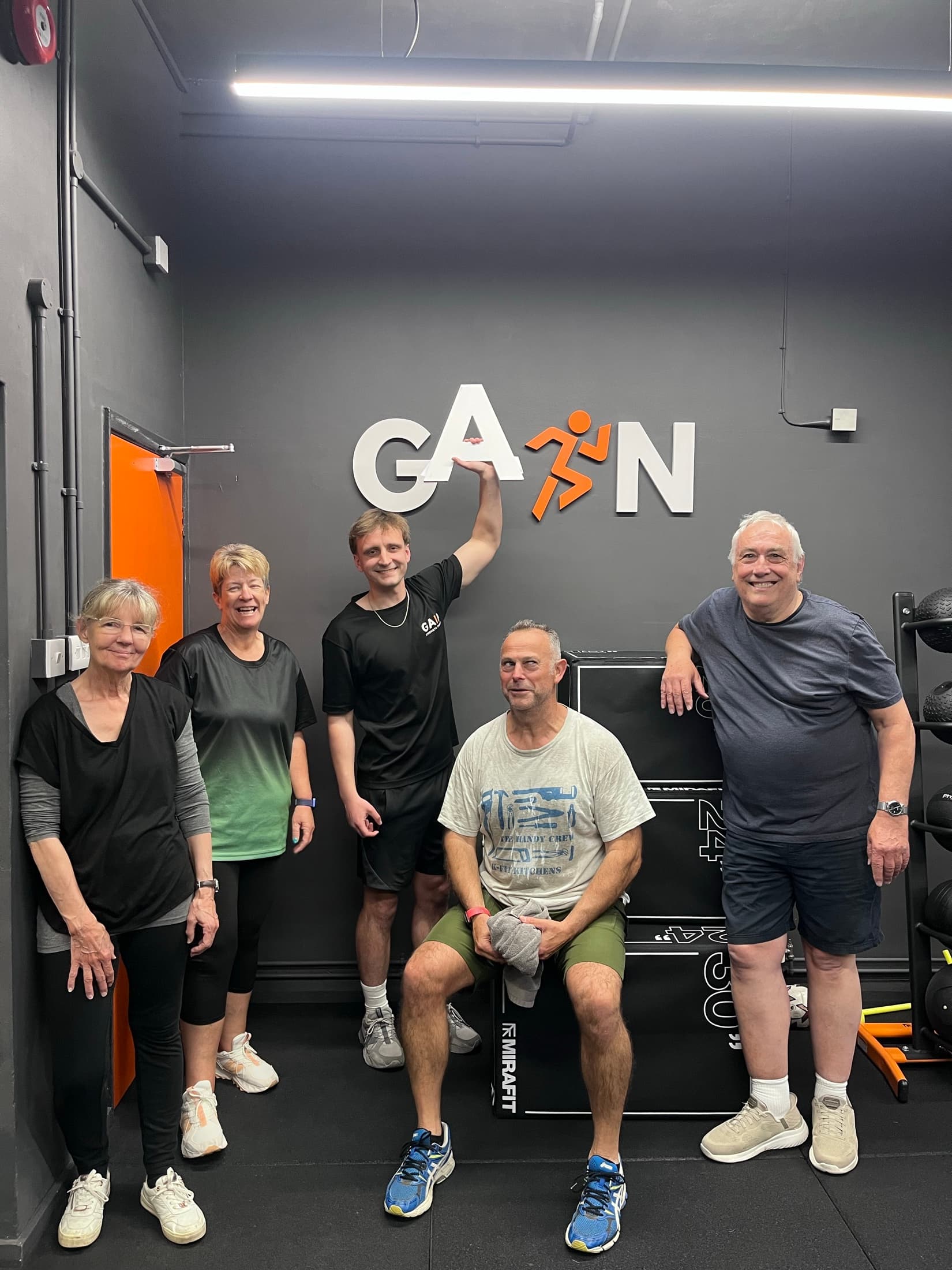 Hallum and four members posing together in front of the GAIN sign